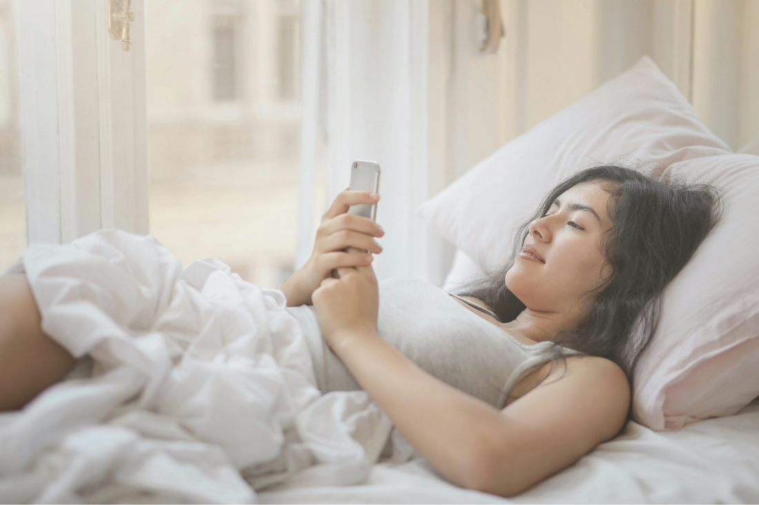 A woman looking at her phone in bed