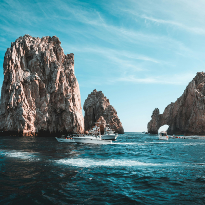 Boats navigating near the Arch of Cabo San Lucas with a clear sky.