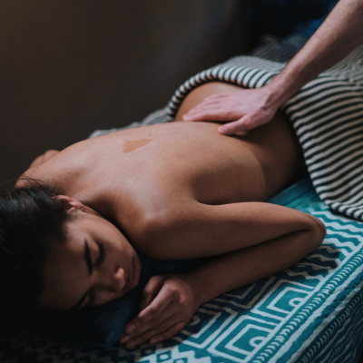 A woman receiving a massage on a bed with a striped blanket