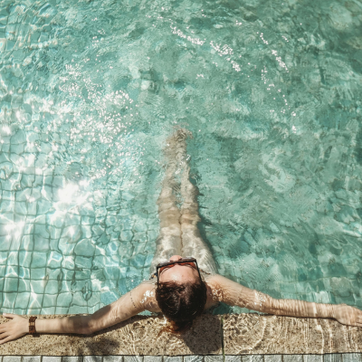 A woman sitting poolside with blue green water