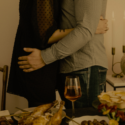 Two people embracing at a dinner table with a glass of wine and food.