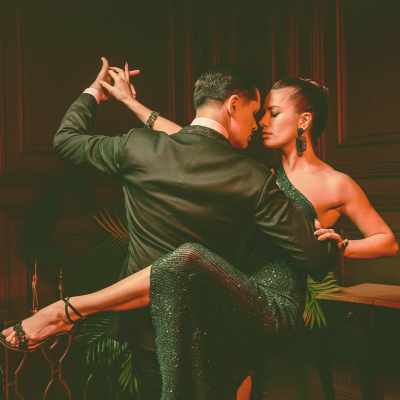 Two attractive dancers in formal attire performing a dance routine on a stage.